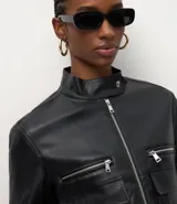 Campera de cuero sintético (PU) color negro, con cuello alto, cierre frontal con cremallera, dos bolsillos superiores con cremallera y dos bolsillos inferiores con solapa.