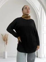 Polera negra de tejido trenzado con cuello alto y puños de cuero color camel.