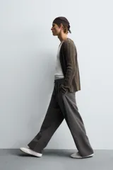 Pantalón de corte relajado, color gris oscuro, con cintura elástica ajustable mediante cordón y pliegues frontales. Presenta bolsillos laterales y bolsillos traseros de parche con pespuntes contrastantes.