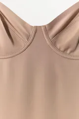 Vestido mini negro con escote corazón y aros integrados en el busto. Presenta tirantes finos ajustables y un diseño entallado con efecto reductor que estiliza la figura.