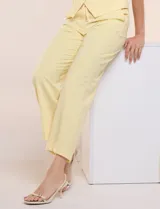 Pantalón sastrero color amarillo, de corte recto y largo al tobillo. Cuenta con cintura con presillas, fino cordón textil para anudar, bolsillos laterales y pinzas de entalle.
