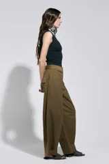 Pantalón tostado de tiro alto y silueta amplia, con costuras marcadas que aportan estructura y cierre frontal con botón metálico.
