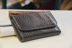 Billetera de cuero marrón con estampado de piel de serpiente, con cierre de broche a presión.