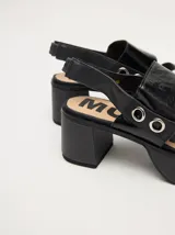 Sandalias de plataforma con taco cuadrado de 6 cm y base de 3 cm. Presentan dos tiras anchas en el empeine con detalles de doble argolla metálica en los laterales y una correa trasera con elástico para mayor ajuste.