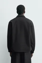 Sobrecamisa de corte regular confeccionada en tejido con mezcla de lana, color marrón oscuro. Presenta cuello solapa, cierre frontal con botones, mangas largas con puños abotonados y bolsillos laterales.