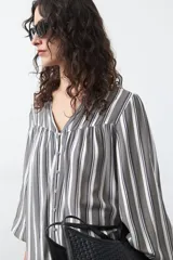 Camisa de manga larga color marrón con estampado de lunares blancos, cuello mao y cierre frontal con botones.