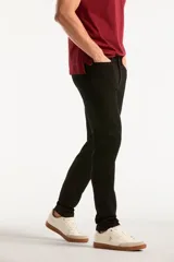 Pantalón de jean negro de corte slim fit, con diseño clásico de cinco bolsillos, presillas para cinturón y cierre frontal con botón y cremallera.