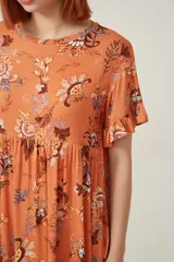 Vestido corto de viscosa con estampado floral en tonos verdes, rojos y blancos. Presenta un diseño holgado con cuello a la base y mangas cortas con volados en los extremos.