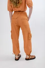 Pantalón cargo color naranja de lino, con cintura elastizada ajustable con cordón, bolsillos laterales con solapa y jareta en el ruedo.