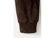 Chaqueta marrón oscuro de piel caprino, con cierre frontal de botones, bolsillos con solapa en el pecho y mangas largas.