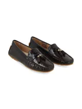 Mocasín de cuero con textura tipo cocodrilo en color marrón chocolate, con detalle de borlas y herraje metálico en el empeine, y suela de goma color caramelo.