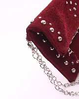 Bandolera de cuero gamuzado color marrón oscuro, con diseño rectangular y solapa frontal decorada con tachas metálicas plateadas. Incluye una cadena metálica plateada larga para usar al hombro o cruzada, y una cadena más corta para llevar como sobre.