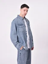 Sobrecamisa de jean celeste con dos bolsillos frontales con solapa y cierre con botones.