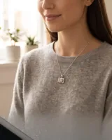 Collar de plata con cadena fina de eslabones y dije colgante en forma de cámara fotográfica decorada con circonias.
