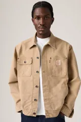 Campera estilo trucker de color marrón claro, confeccionada en gabardina resistente. Cuenta con cuello clásico, cierre frontal de botones metálicos, bolsillos frontales con solapa y bolsillos laterales ribeteados.
