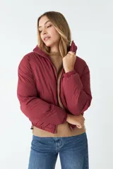 Campera puffer color borgoña de nylon con cuello alto, cierre frontal y bolsillos laterales.