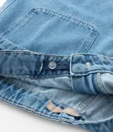 Bermuda de jeans de algodón, color azul medio, de corte amplio y largo hasta la rodilla. Presenta tiro alto con ajuste elástico interno en la cintura y bolsillos frontales.