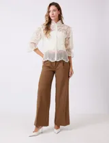 Blusa Liv Los Angeles confeccionada en tul bordado color beige, de cuello alto, cierre frontal con botones y mangas tres cuartos con terminación amplia.