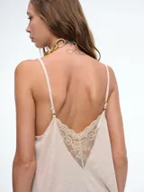 Top lencero de tirantes finos, color blanco, con escote en V decorado con encaje. Presenta una silueta holgada y liviana.