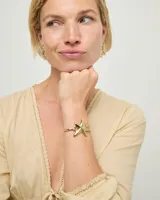 Pulsera rígida de metal dorado con diseño de estrella de mar y detalle de resorte.