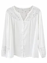 Camisa blanca con detalles bordados en ojalillo en el canesú y en los puños, escote en V y cierre frontal con botones.