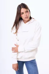 Buzo tipo canguro oversize de color blanco, con capucha y bolsillo frontal. Presenta un estampado artístico de una galaxia con estrellas en tonos violetas en la parte trasera.