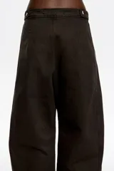 Pantalón de corte barrel y tiro medio, confeccionado en mezcla de algodón. Presenta cierre frontal oculto con botón y cremallera, bolsillos laterales y costadillos que estructuran la silueta.