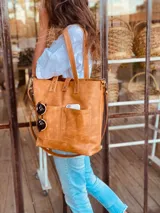 Bolso tipo tote bag color suela, de cuero, con doble asa de mano y correa larga extraíble y ajustable. Tiene dos bolsillos externos grandes.