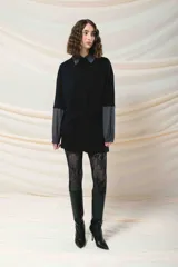 Remerón negro con cuello camisero, mangas largas con puños elásticos y bolsillo con solapa en el pecho.