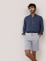 Bermuda de hombre de corte regular fit, color gris, con cierre de cremallera y botón, bolsillos laterales y traseros.