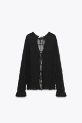 Top de manga larga negro, de tejido de punto semitransparente con efecto fruncido horizontal. Presenta cuello redondo con borde festoneado y cierre frontal con lazos finos.