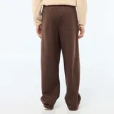 Pantalón de corte ancho y estilo relajado, confeccionado en tejido de color marrón, con cintura elástica y diseño minimalista.