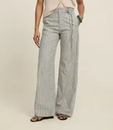 Pantalón wide leg de sarga con rayas verticales en blanco y negro, cintura alta con cinturón fino y trabillas.