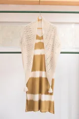 Chal triangular tejido a mano en lana de alpaca natural color crudo, con diseño calado y terminación con borlas.