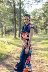 Vestido midi azul marino con estampado de flores rojas, naranjas y rosas. Tiene cuello drapeado y corte ajustado al cuerpo.