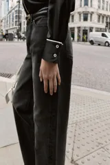 Camisa de corte amplio confeccionada en tejido satinado, con cuello solapa y manga larga. Presenta detalles de vivos en contraste y cierre frontal con botones ocultos.