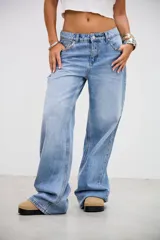 Pantalón de denim tiro bajo, color gris lavado, de corte recto y holgado. Presenta una línea de tachas metálicas pequeñas a lo largo de la costura lateral externa.