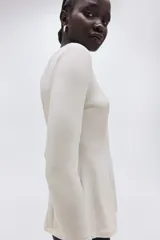 Top de manga larga confeccionado en punto de crepé, con cuello redondo y diseño de peplum. Presenta costuras moldeadoras tanto en el frente como en la espalda.