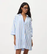 Salida de playa tipo camisa confeccionada en voile de algodón, con diseño de rayas verticales en tonos celeste y blanco, cuello tradicional y mangas 3/4.