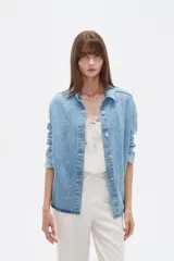 Campera de jean de corte holgado, con cuello camisero, cierre frontal con botones metálicos y mangas largas.