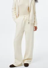 Pantalón de corte recto y holgado, color blanco, con cintura elástica y cordón ajustable. Presenta costuras verticales frontales que estilizan la silueta.