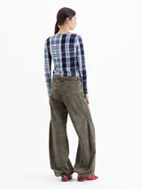 Pantalón wide leg de denim con lavado efecto gastado en tono verde oliva. Presenta cinco bolsillos, cierre frontal con botón y un cinturón integrado del mismo tejido con doble hebilla metálica.