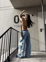 Jeans rígido de corte wide leg, tiro medio y color celeste, con diseño de estrellas grandes desflecadas en los laterales de las piernas.