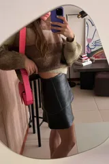 Minifalda negra de cuero sintético con corte campana y costuras decorativas en hilo blanco.