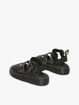 Sandalia Dr. Martens Gryphon Quad negra con plataforma, fabricada con piel Pisa. Presenta tres correas ajustables con hebillas de latón, pespuntes amarillos distintivos en la suela y tirador trasero con el logo AirWair.