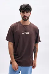 Remera de manga corta color marrón oscuro, corte oversize, con cuello redondo y estampado frontal con el texto "UNIVERSAL FUTURE" en color crema.