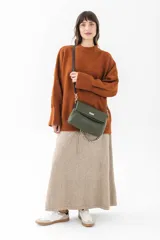 Cartera de hombro color beige, con solapa frontal y correa ajustable combinada en cuero liso negro y cadena metálica plateada.