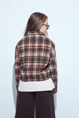 Campera de paño con diseño de cuadros en tonos negro, gris y beige. Presenta cuello camisero, cierre frontal con botones y corte corto.