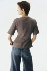 Remera de manga corta color marrón topo en punto interlock pesado, con cuello redondo y diseño entallado en la cintura con pinzas moldeadoras en el frente que generan una silueta peplum.
