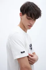 Remera blanca de algodón con cuello redondo y manga corta. Estampado fotográfico en el pecho con texto.